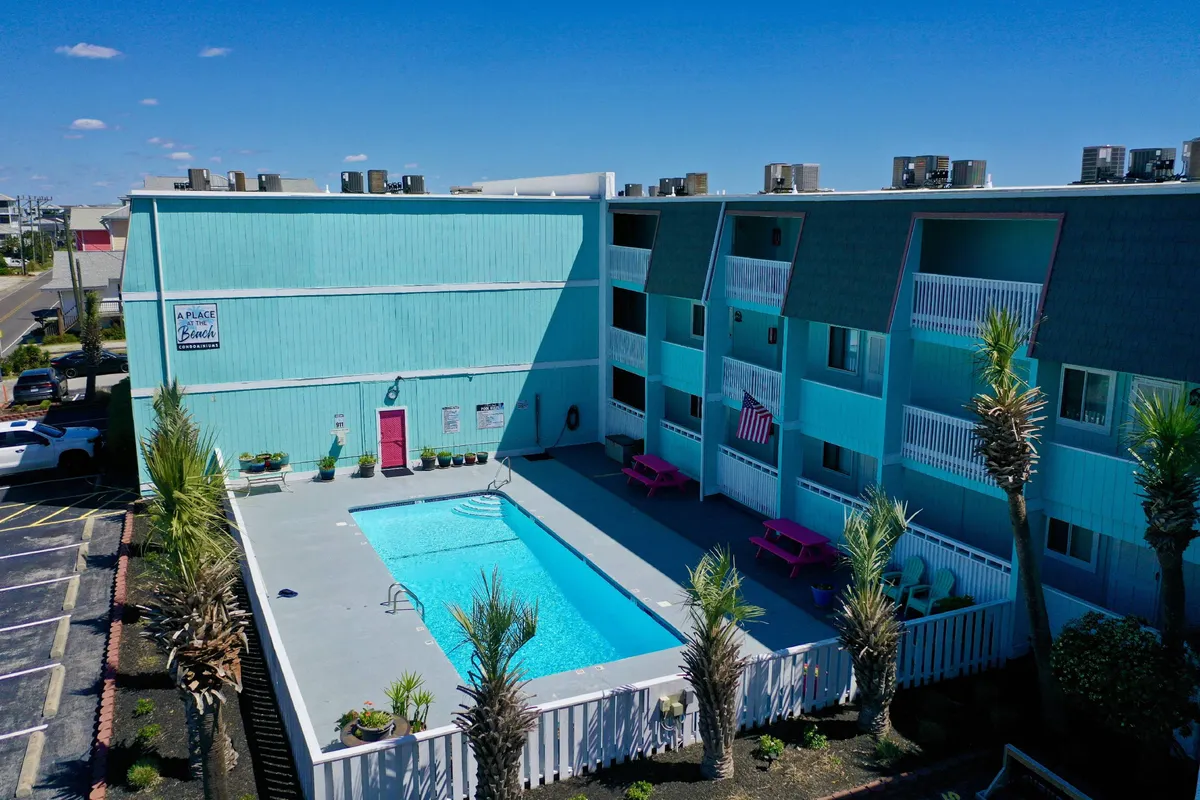 Another perspective of the community pool, this time featuring pink picnic tables and palm trees, further emphasizing spaces for outdoor dining and poolside lounging. The relaxed atmosphere hints at the possibility of pool parties, alfresco meals, and casual gatherings.